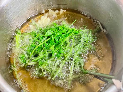 ニンジン間引き菜をスプーンでまとめて油で揚げる